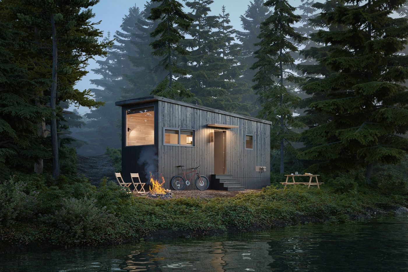 The Nook Studio park model tiny home by Zook Cabins, a compact modern cabin with dark wood siding and a corner window beside a lake