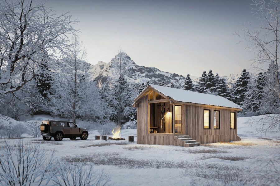 The Yukon park model tiny home by Zook Cabins with a front porch in a snowy mountain setting